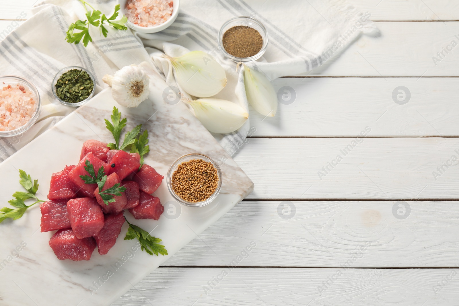 Photo of Raw beef meat and different ingredients for cooking delicious goulash on white wooden table, flat lay. Space for text