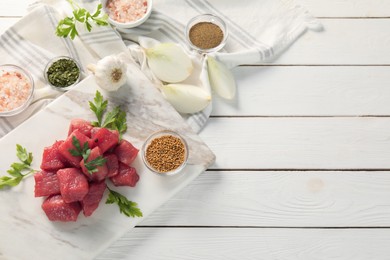 Raw beef meat and different ingredients for cooking delicious goulash on white wooden table, flat lay. Space for text