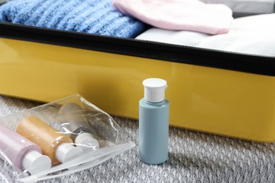 Photo of Plastic bag of cosmetic travel kit and suitcase on bed