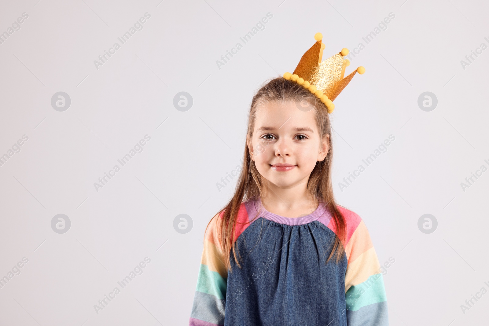 Photo of Cute girl in golden crown on light grey background, space for text. Little princess