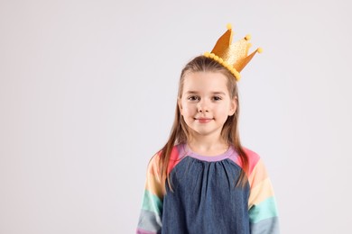 Cute girl in golden crown on light grey background, space for text. Little princess