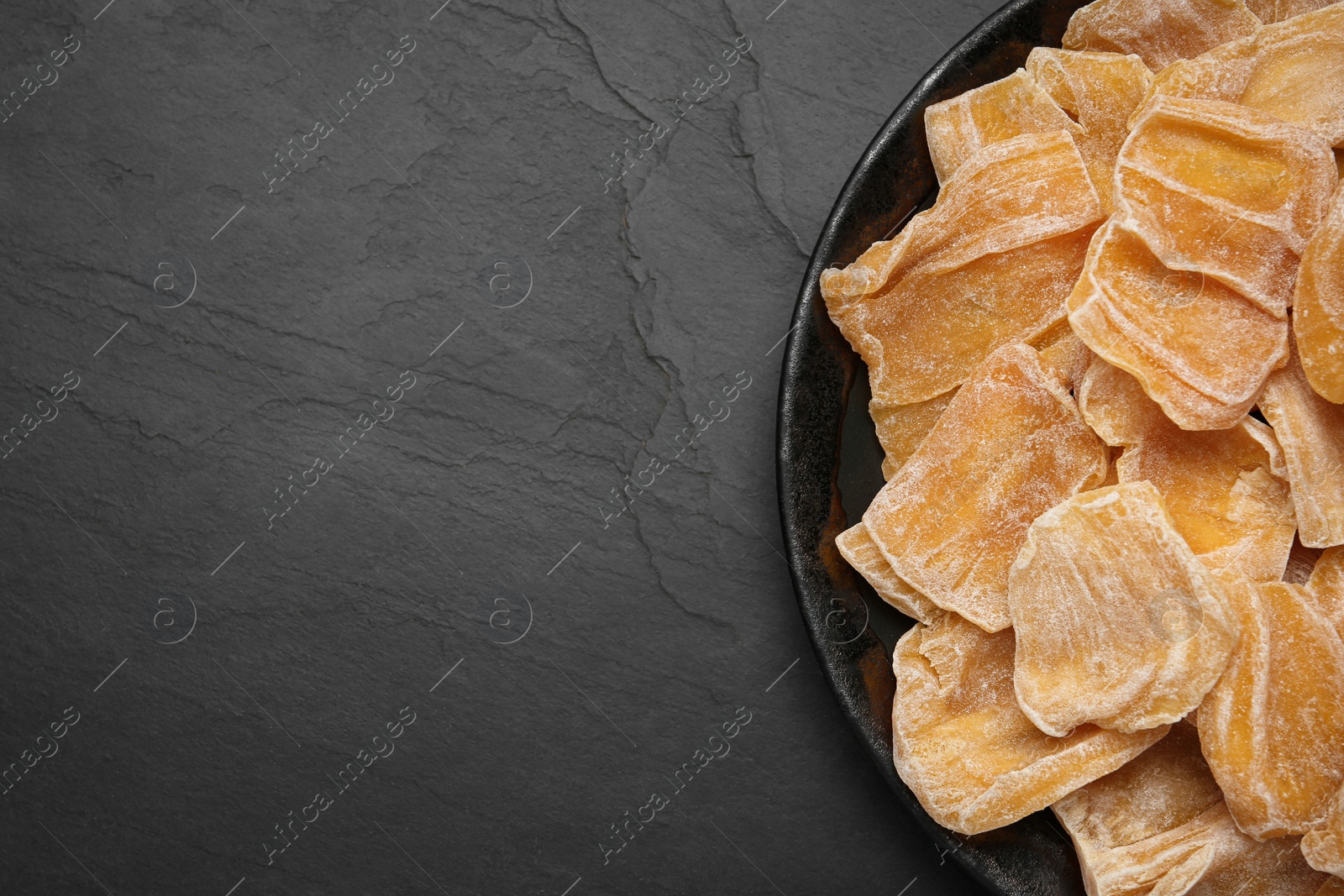 Photo of Delicious dried jackfruit slices on black table, top view. Space for text