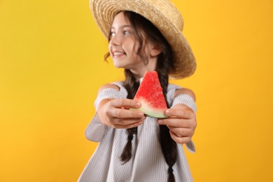 Photo of Cute little girl against yellow background, focus on hands with watermelon