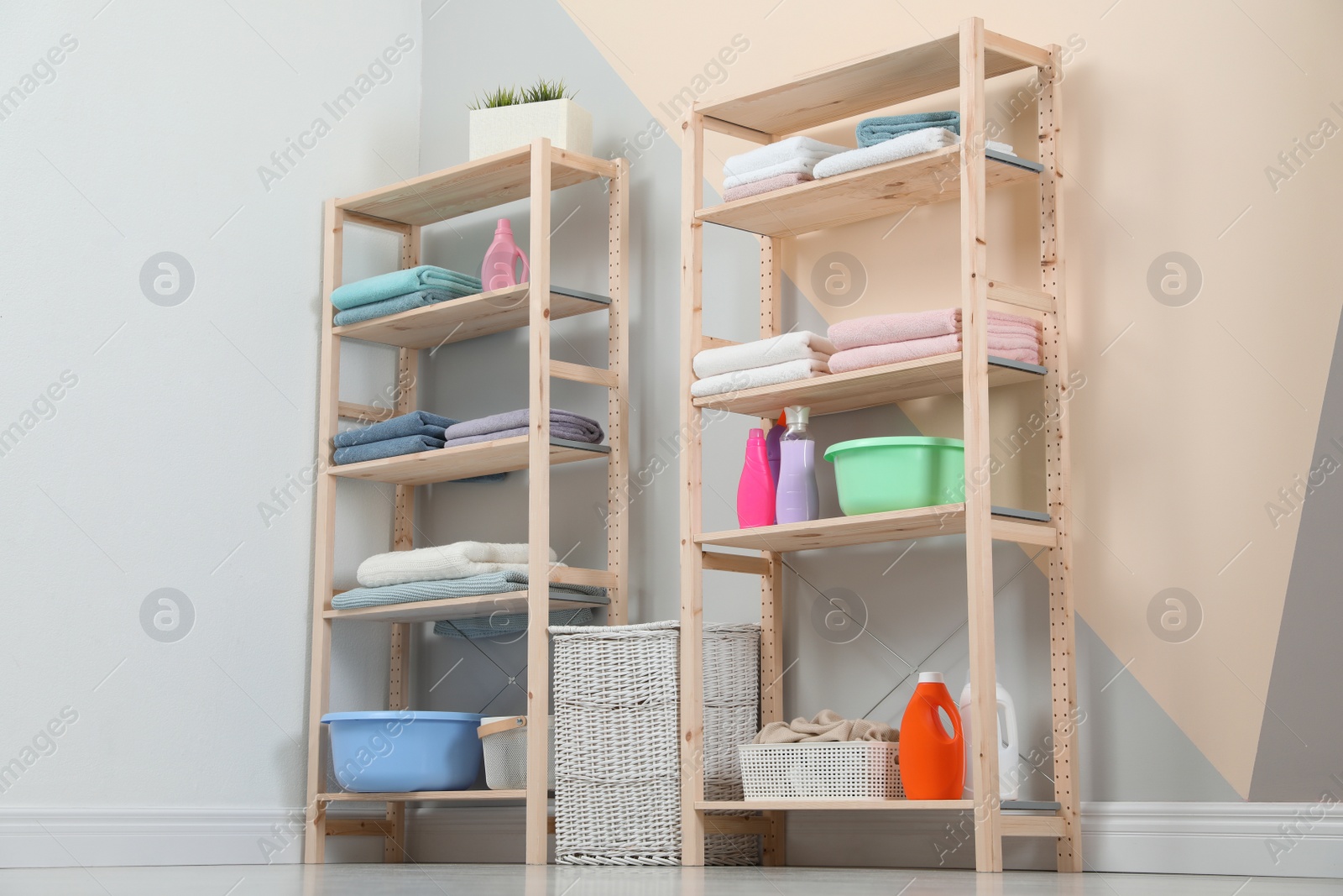 Photo of Wooden shelving units with clean towels and detergents in stylish room interior