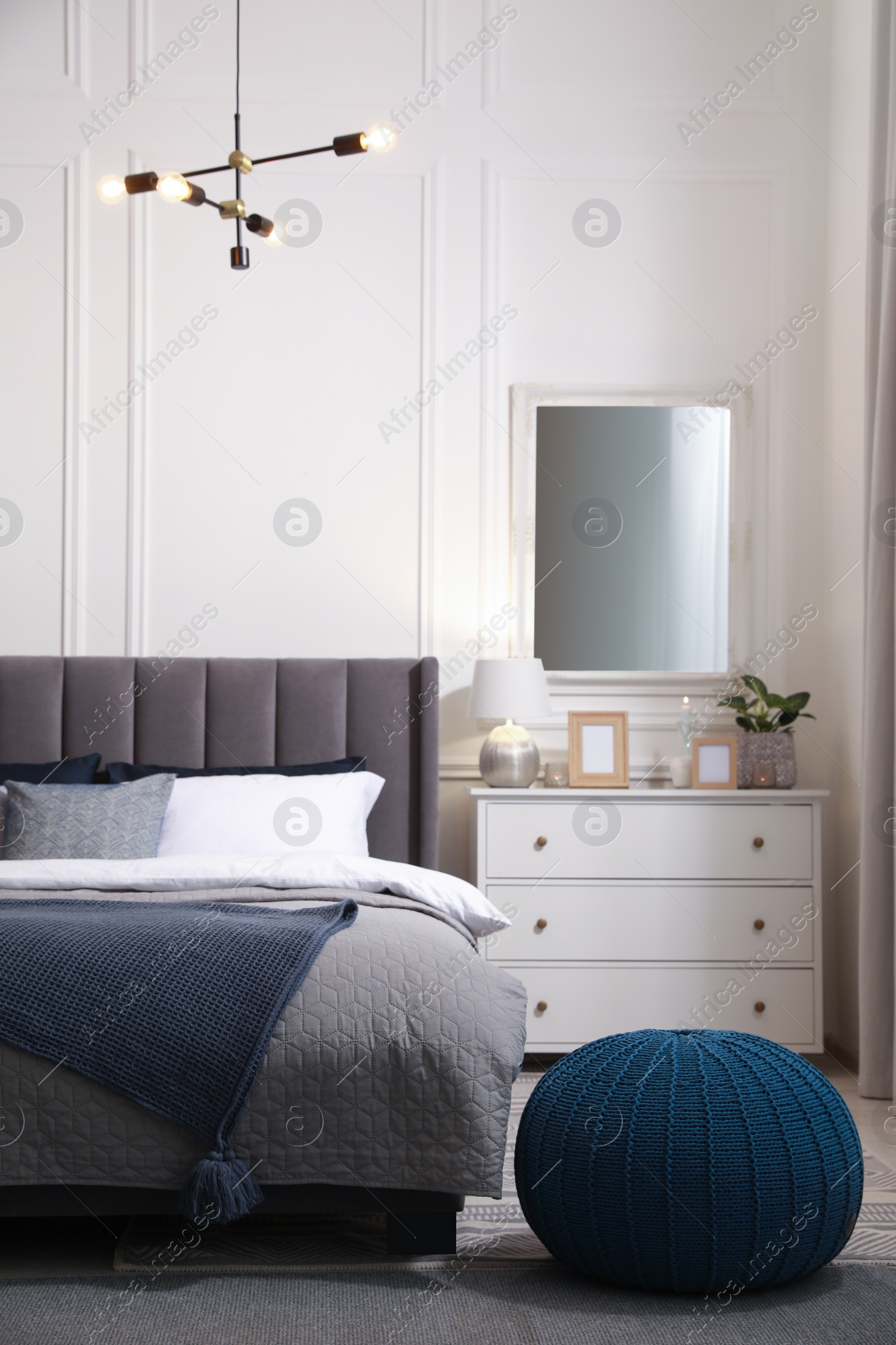 Photo of Stylish bedroom interior with large comfortable bed and chest of drawers