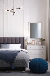 Stylish bedroom interior with large comfortable bed and chest of drawers