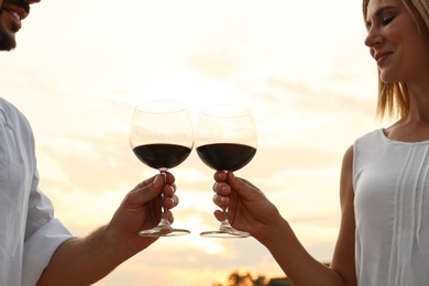 Photo of Happy romantic couple drinking wine together on beach, closeup view