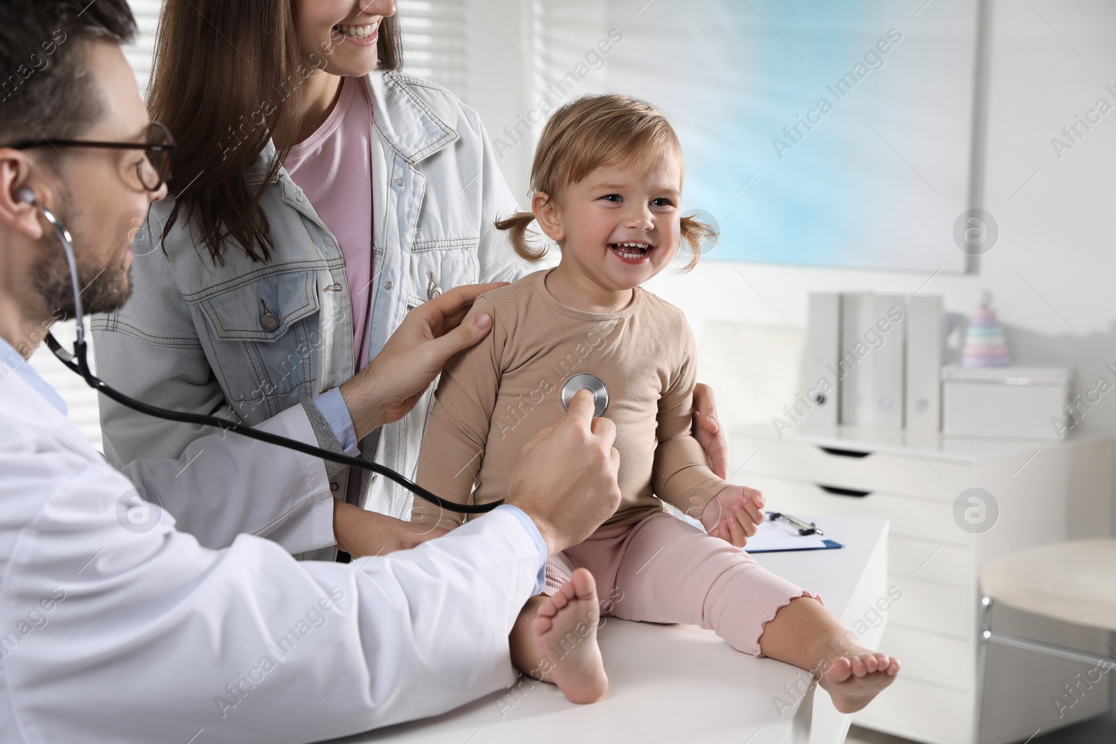 Photo of Mother and her cute baby having appointment with pediatrician in clinic. Doctor examining little girl