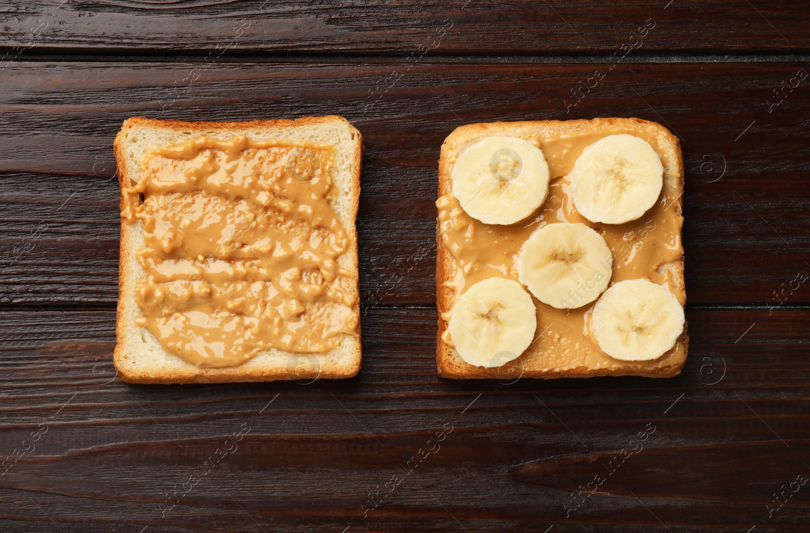 Photo of Delicious toasts with peanut butter and banana on dark wooden table, flat lay