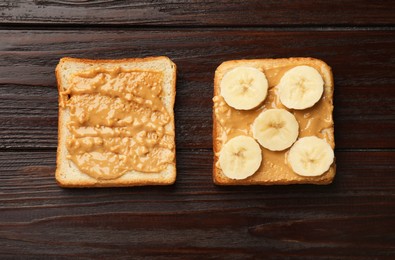 Photo of Delicious toasts with peanut butter and banana on dark wooden table, flat lay