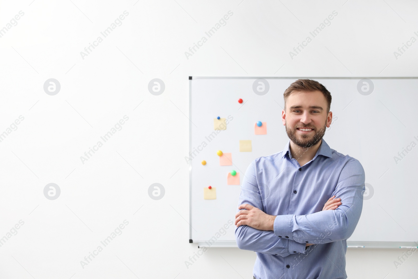 Photo of Portrait of young teacher near whiteboard in classroom. Space for text