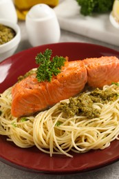 Delicious spaghetti with salmon and pesto sauce on light grey table, closeup