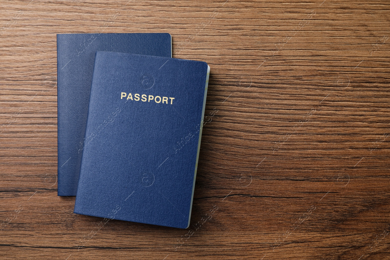 Photo of Blank blue passports on wooden table, flat lay with space for text