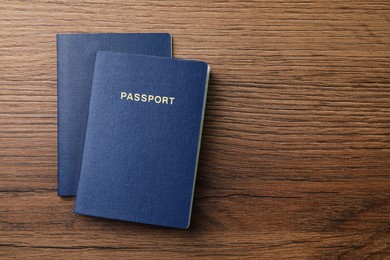 Photo of Blank blue passports on wooden table, flat lay with space for text