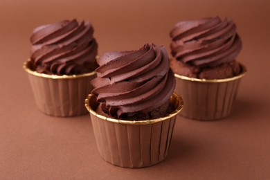 Photo of Delicious chocolate cupcakes on brown background, closeup