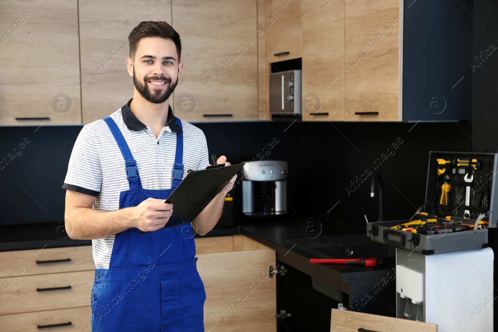 Photo of Male plumber with clipboard in kitchen. Repair service