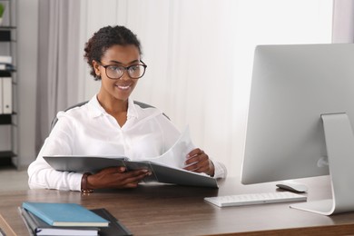 African American intern with folder working at table in office