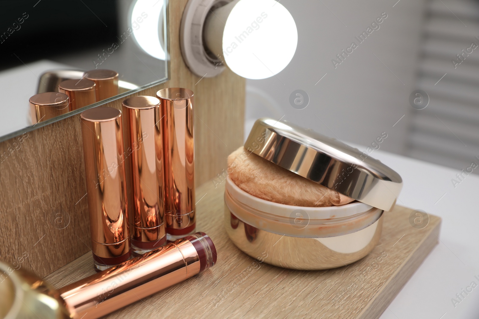 Photo of Lipsticks and powder on dressing table, closeup view