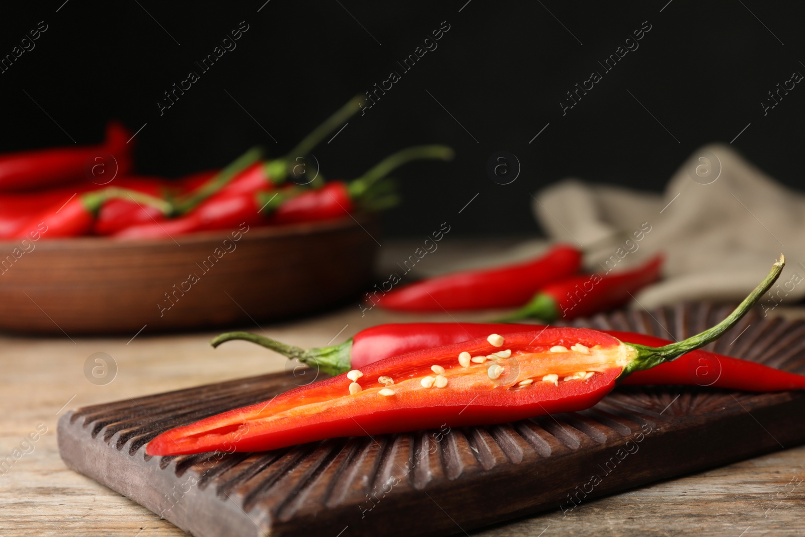 Photo of Board with red hot chili peppers on wooden table. Space for text