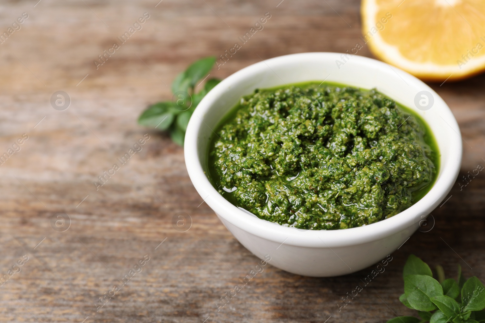 Photo of Homemade basil pesto sauce in bowl on table