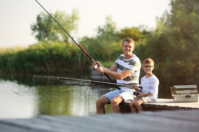 Dad and son fishing together on sunny day