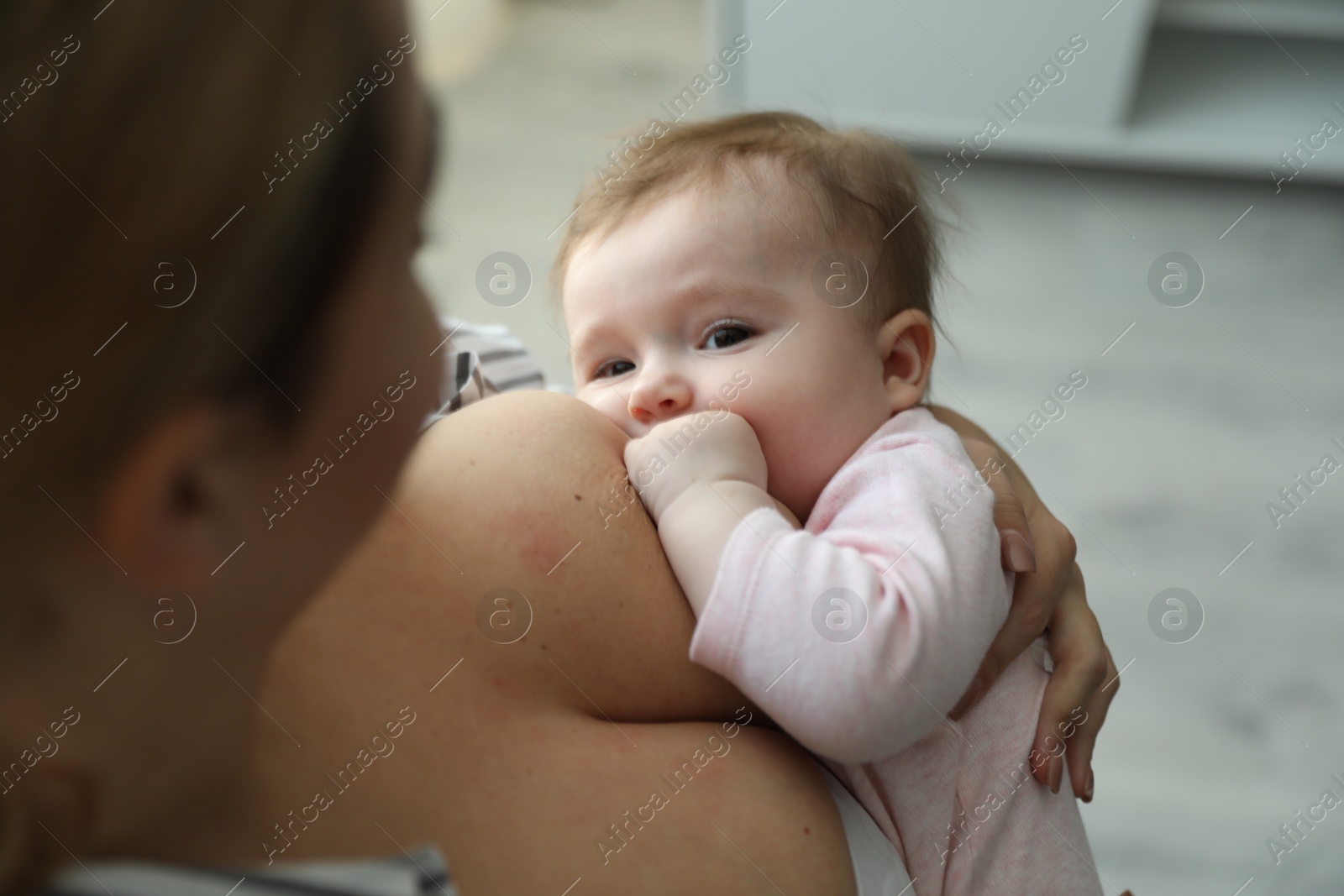 Photo of Young woman breastfeeding her baby at home, closeup