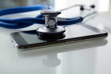 Photo of Smartphone and stethoscope on light table, closeup. Repairing service