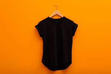 Photo of Hanger with blank t-shirt on color background. Mockup for design