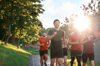 Photo of Group of people running outdoors on sunny day. Space for text