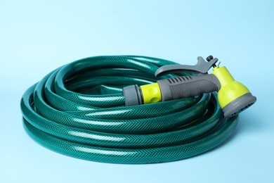 Photo of Watering hose with sprinkler on light blue background