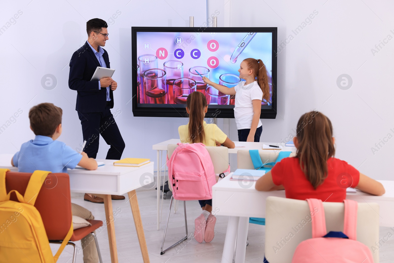 Photo of Teacher and pupil using interactive board in classroom during lesson