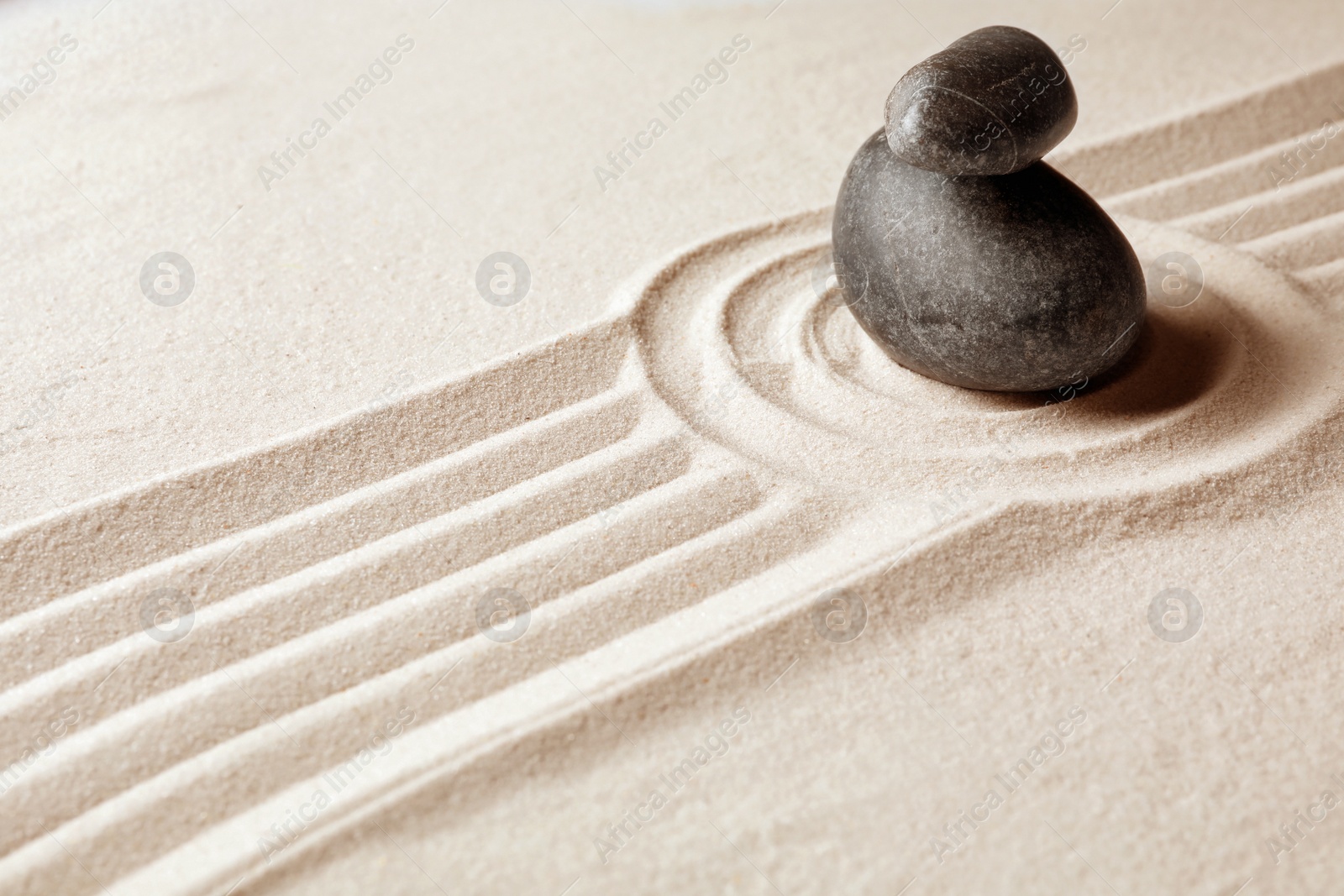 Photo of Stacked zen garden stones on sand with pattern, space for text. Meditation and harmony