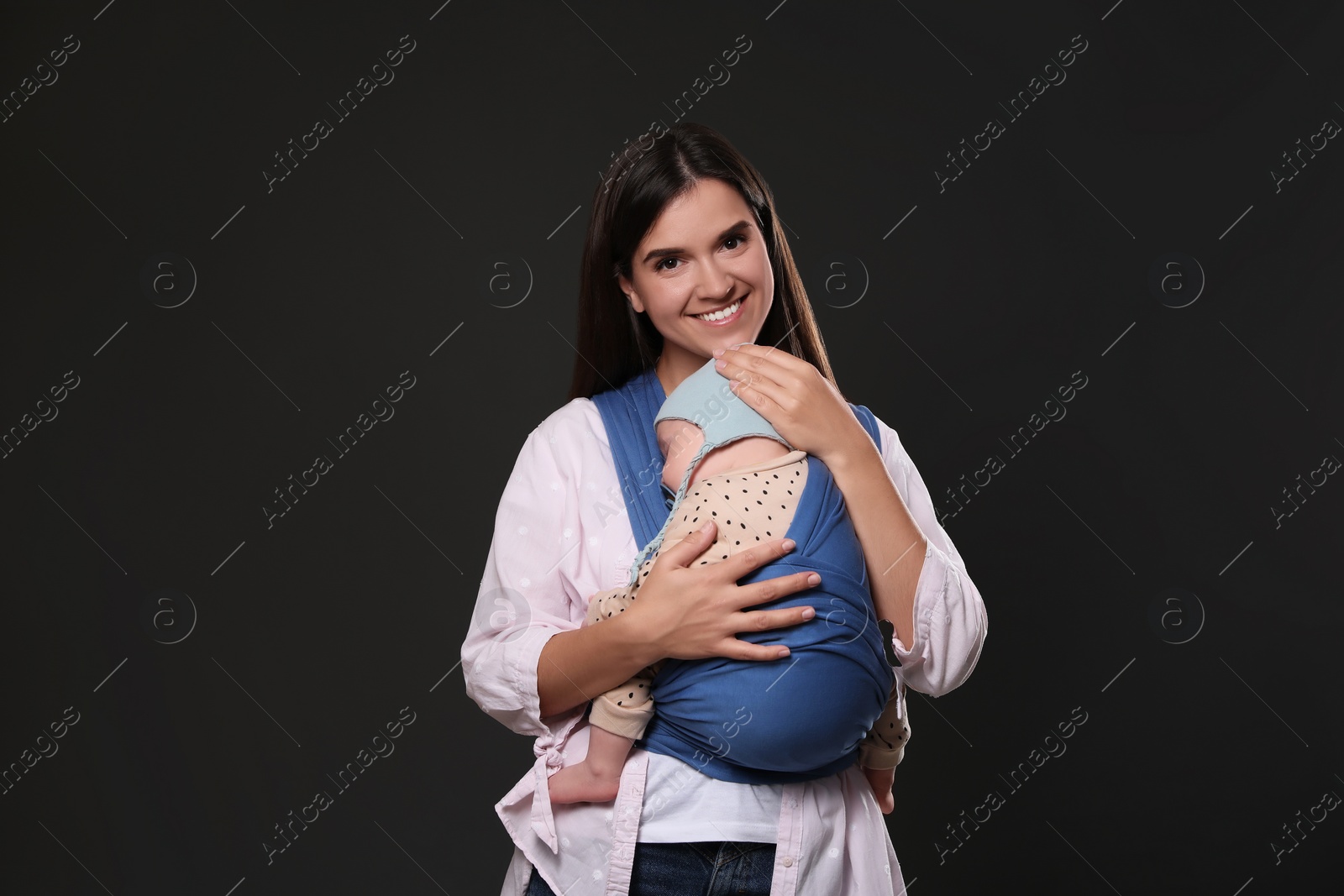 Photo of Mother holding her child in sling (baby carrier) on black background