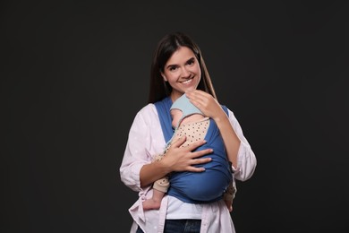 Photo of Mother holding her child in sling (baby carrier) on black background