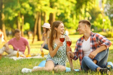 Photo of Young couple enjoying picnic in park on summer day