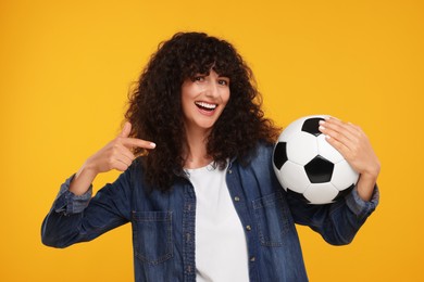 Photo of Happy fan showing soccer ball on yellow background