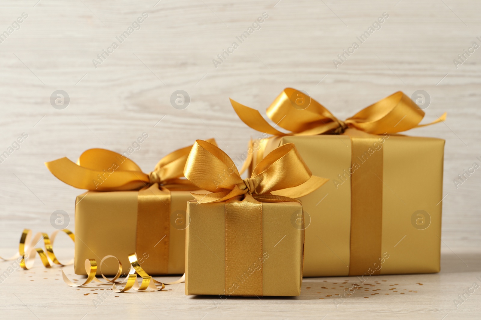 Photo of Beautifully wrapped gift boxes and confetti on white wooden table