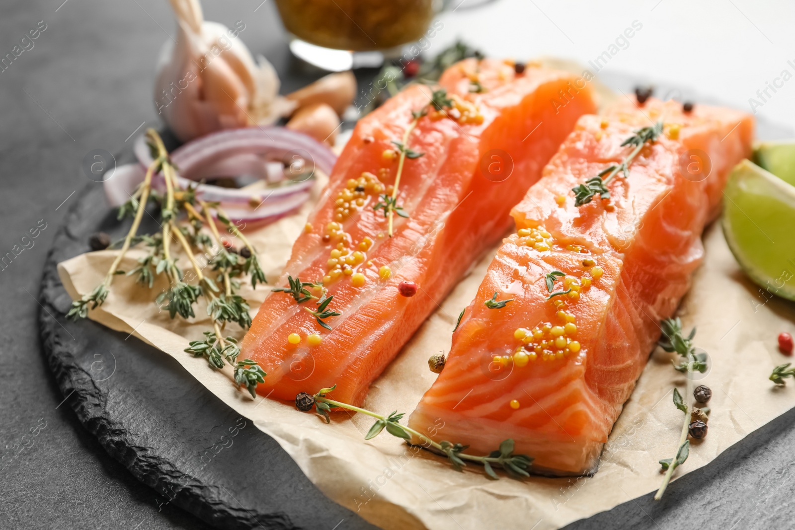 Photo of Fresh salmon and ingredients for marinade on slate plate, closeup