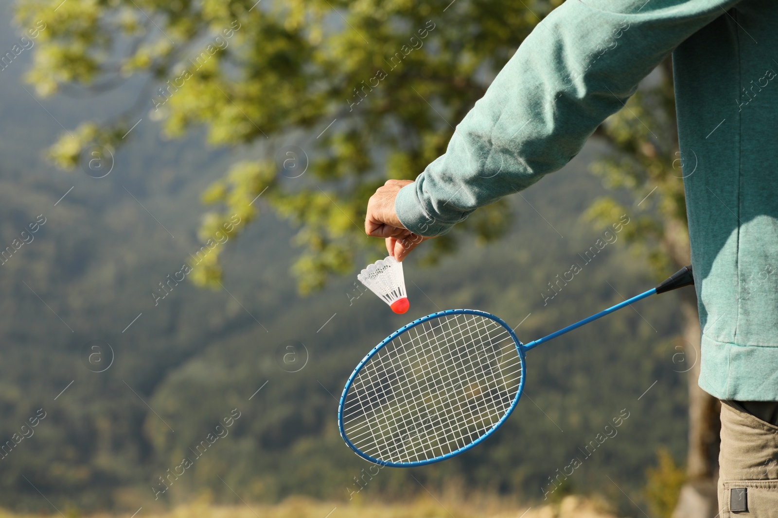 Photo of Man playing badminton outdoors on sunny day, closeup. Space for text