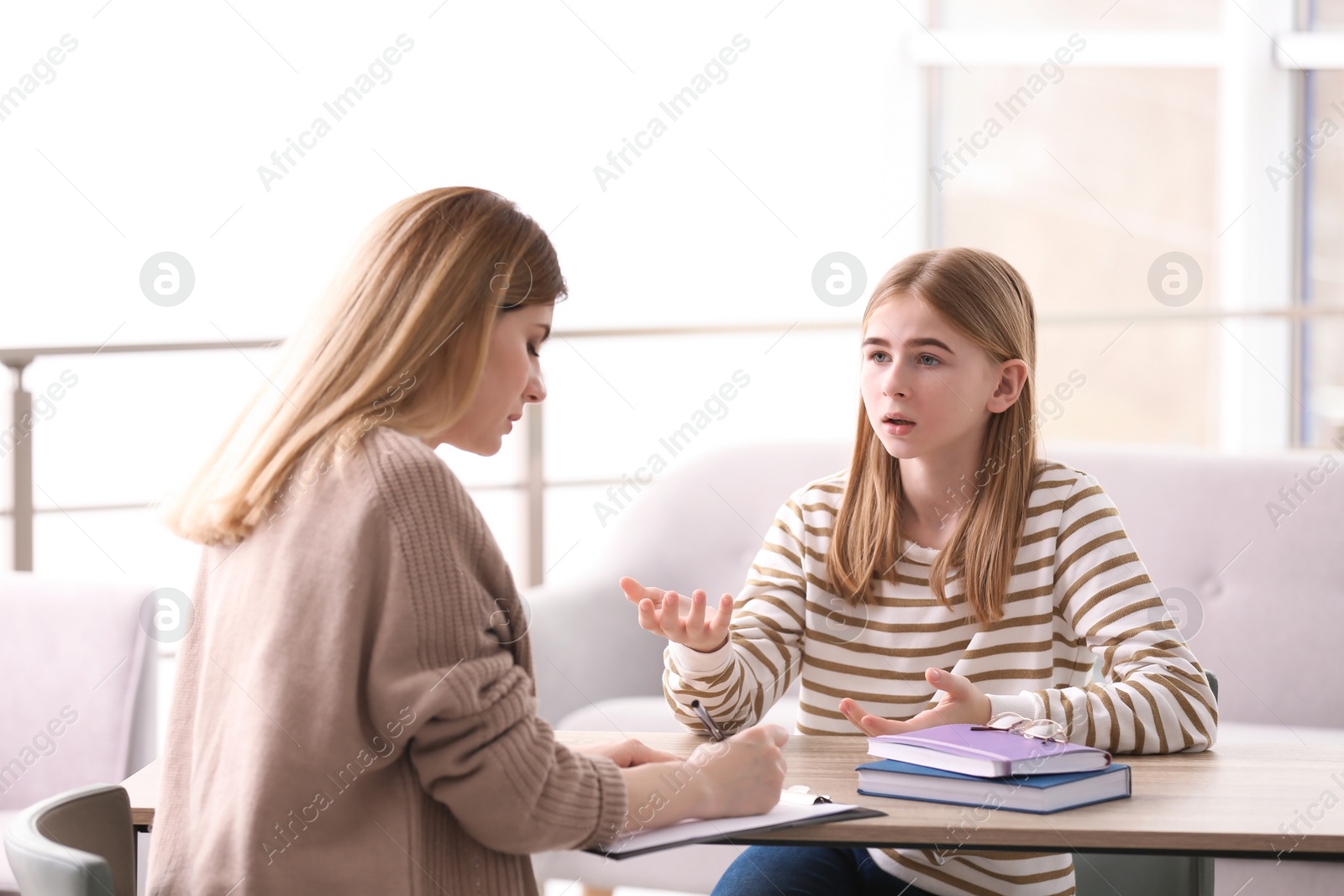 Photo of Young female psychologist working with teenage girl in office