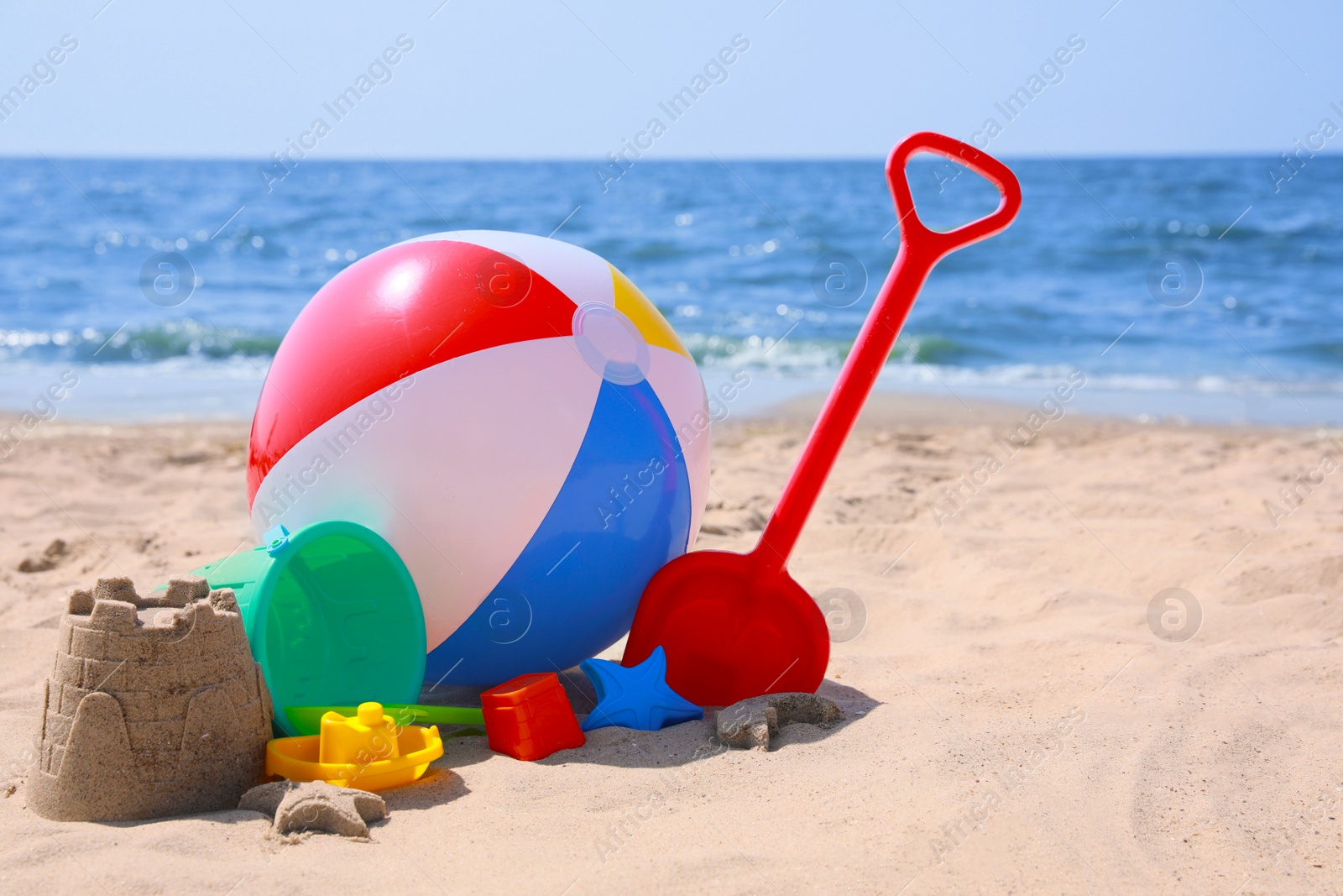 Photo of Different sand toys and beach ball near sea
