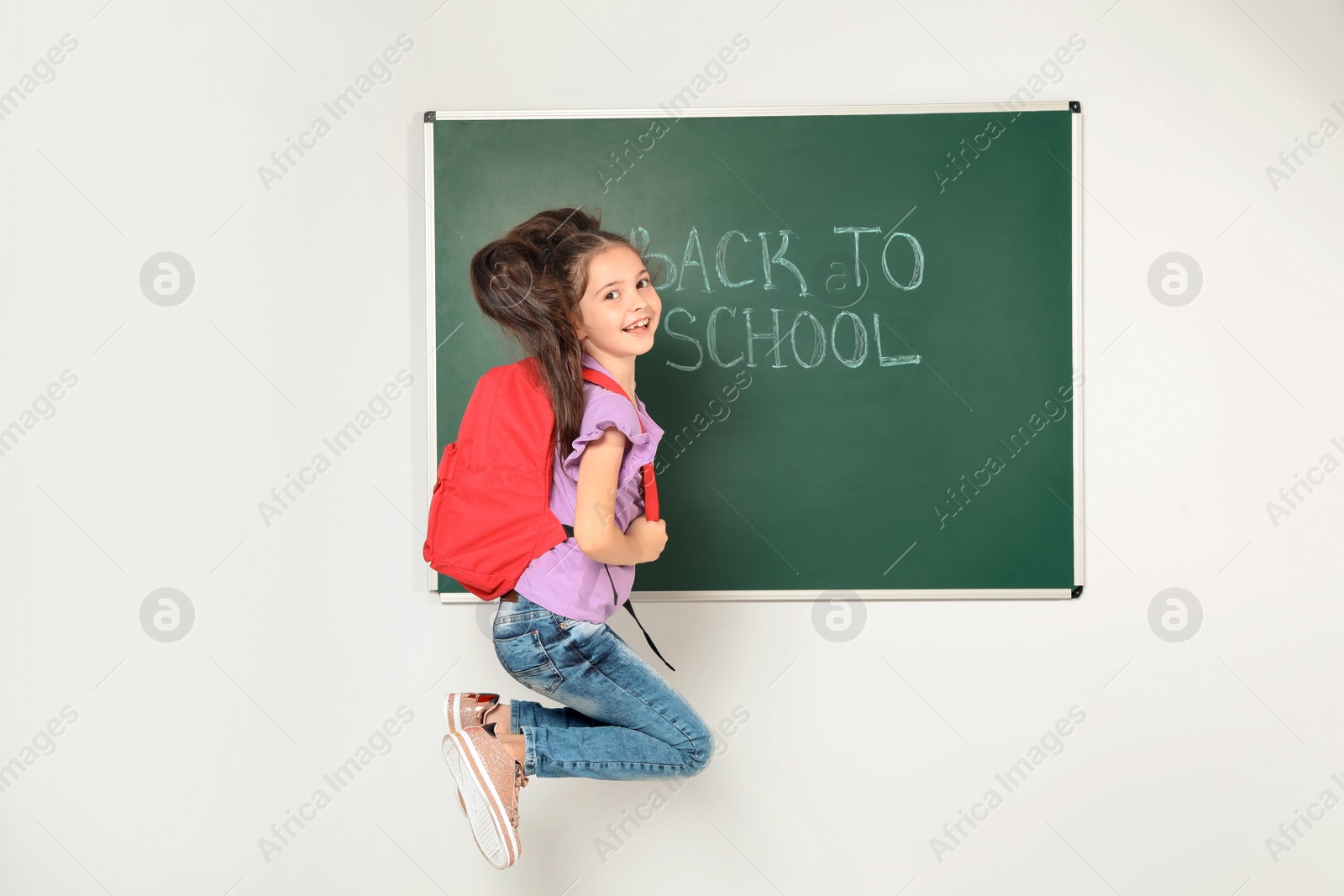Photo of Little child near chalkboard with text BACK TO SCHOOL