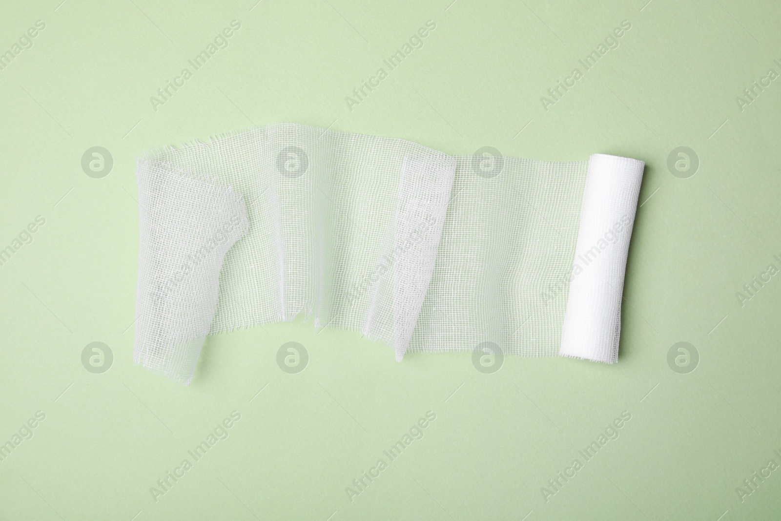 Photo of White medical bandage on light green background, top view