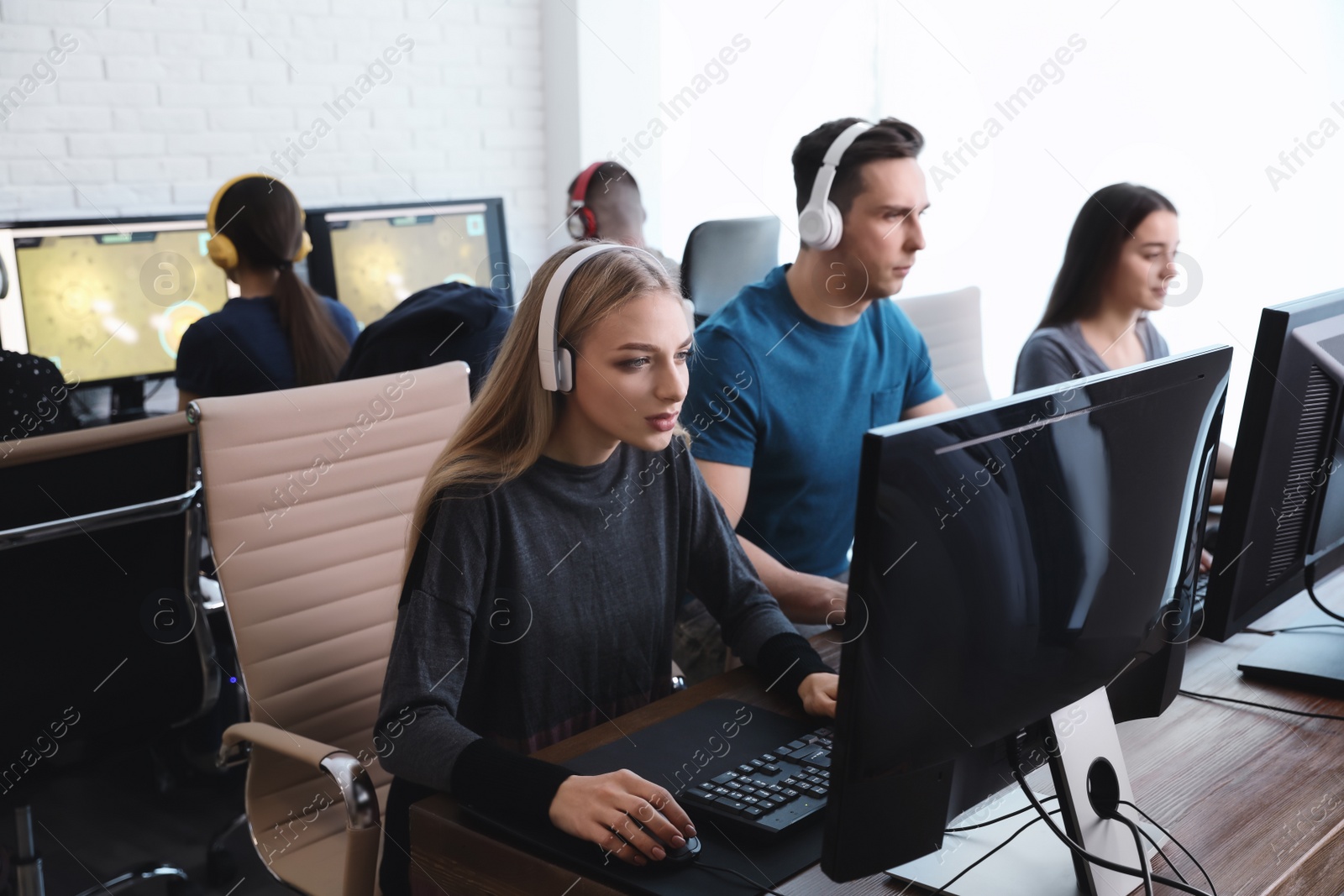 Photo of Young people playing video games on computers indoors. Esports tournament