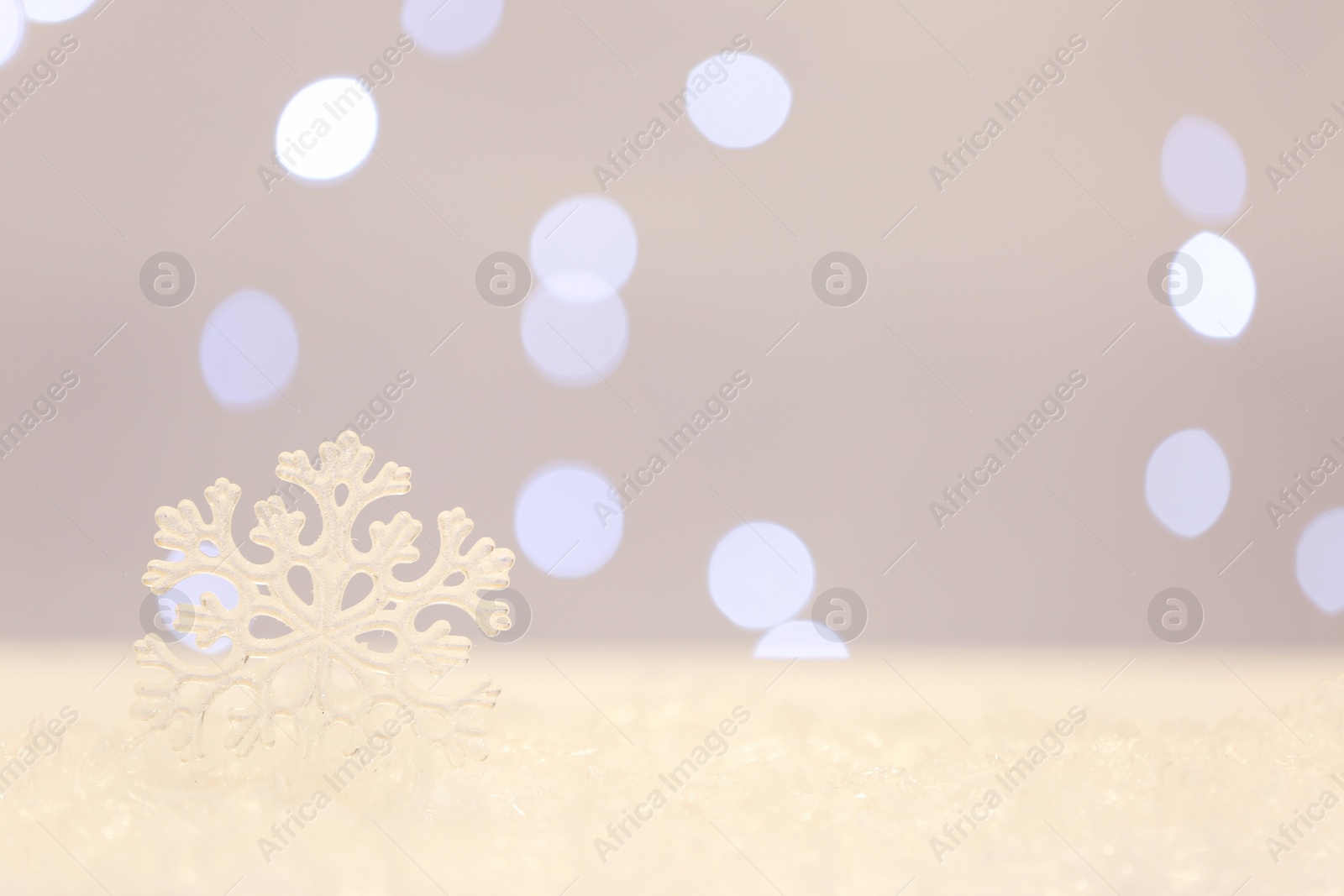 Photo of Beautiful decorative snowflake against blurred festive lights. Space for text