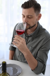 Photo of Man with glass of wine at table in restaurant