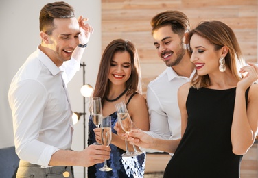 Friends clinking glasses with champagne at party indoors