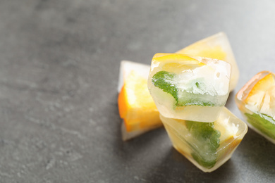 Photo of Ice cubes with orange and mint on grey table, closeup. Space for text