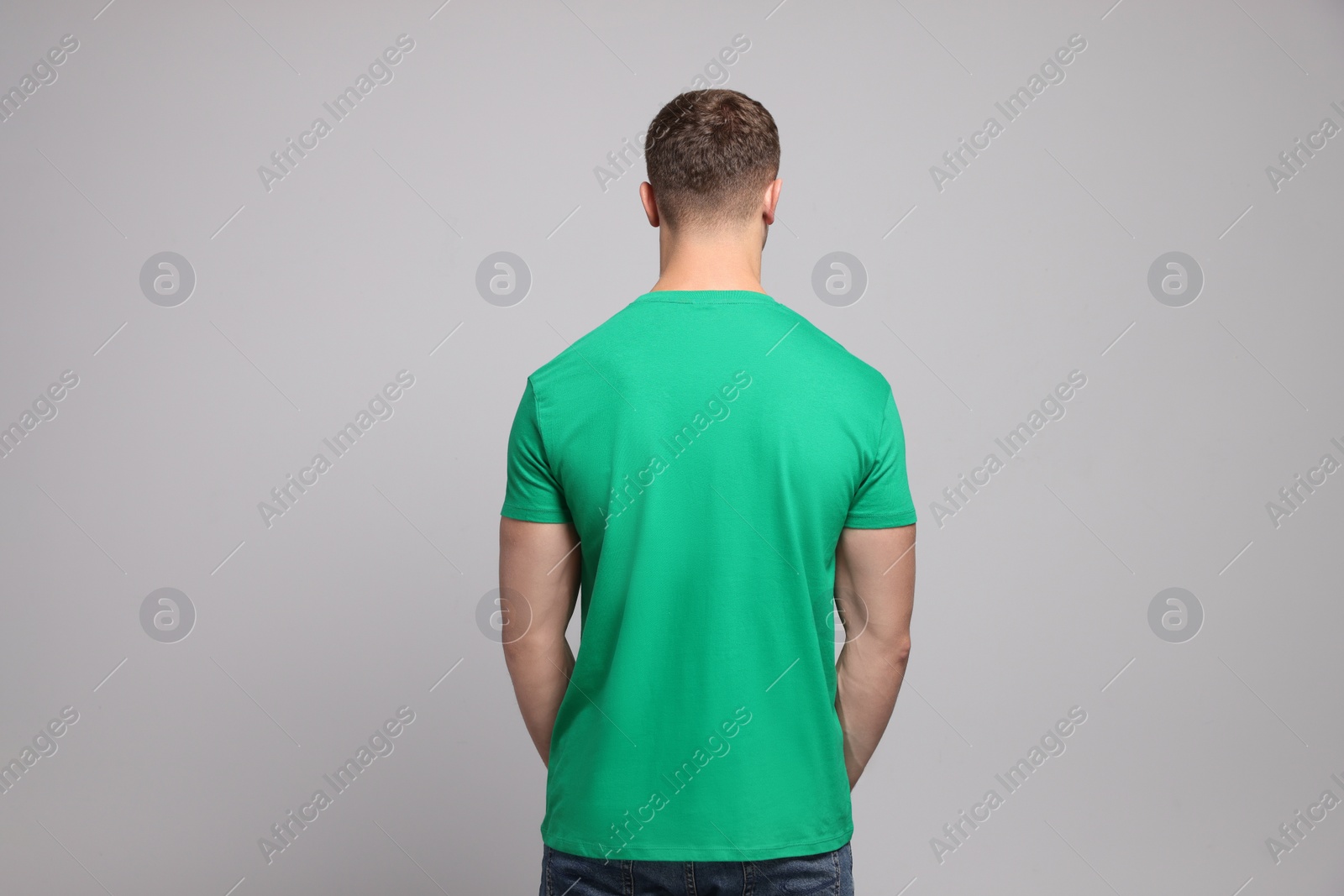 Photo of Man wearing green t-shirt on light grey background, back view. Mockup for design