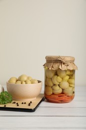 Photo of Tasty pickled mushrooms and spices on white wooden table